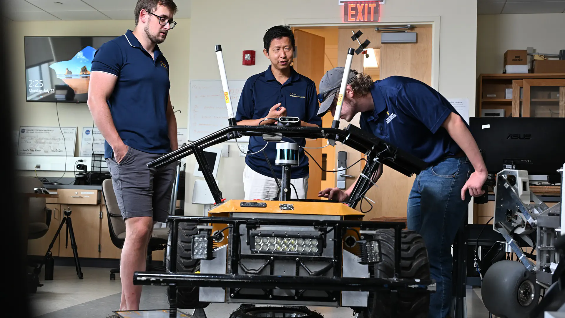 Students and a teacher working on a robot in a Robotics Lab.