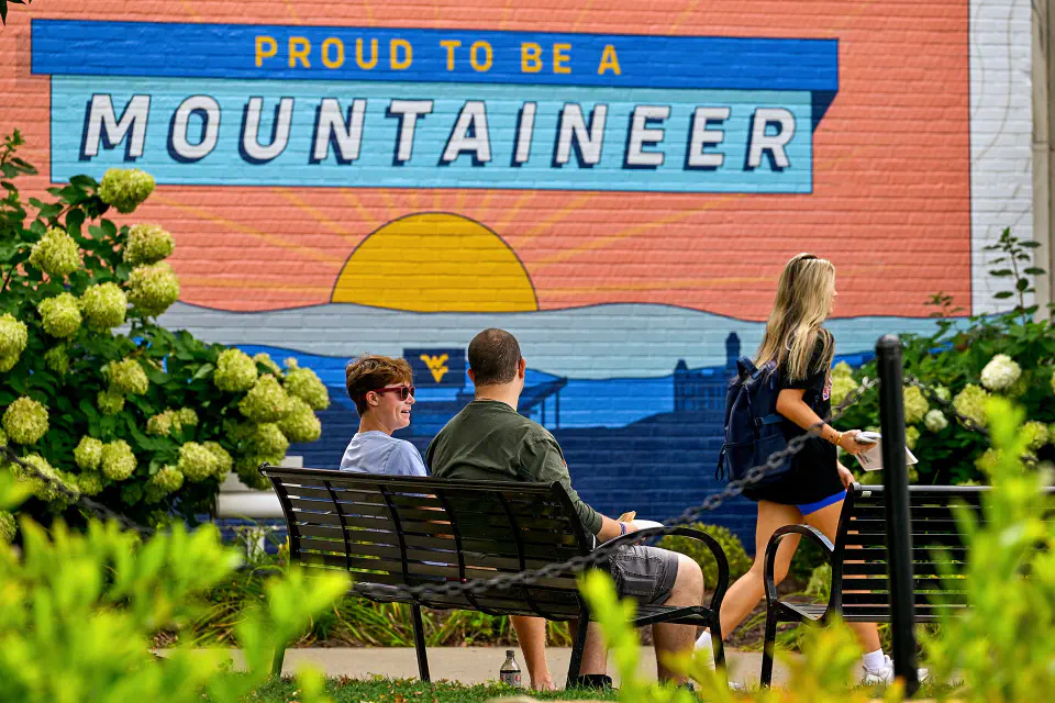 Students sitting and walking in front of the new Mountainlair mural