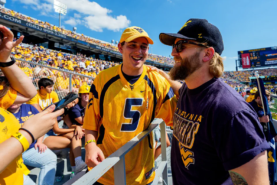 WVU alum Charles Wesley Godwin with a WVU student in the Mountaineer Maniacs section of the stadium