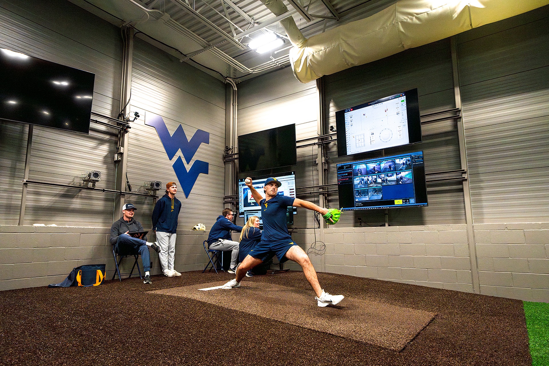 Students taking metrics of a baseball player's pitch in a sports science lab