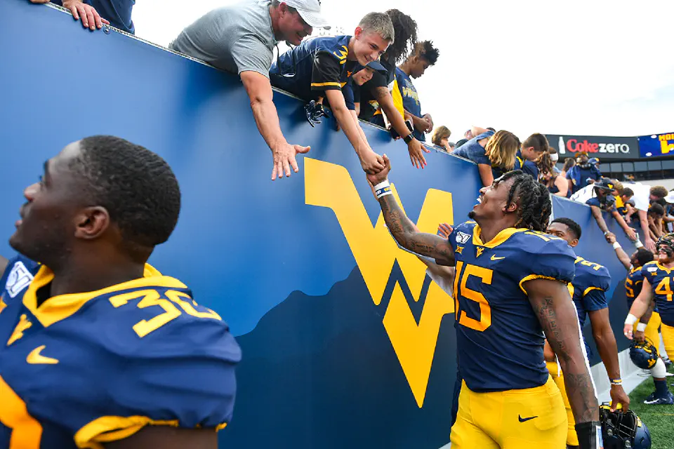 A WVU football player shaking hands with a fan