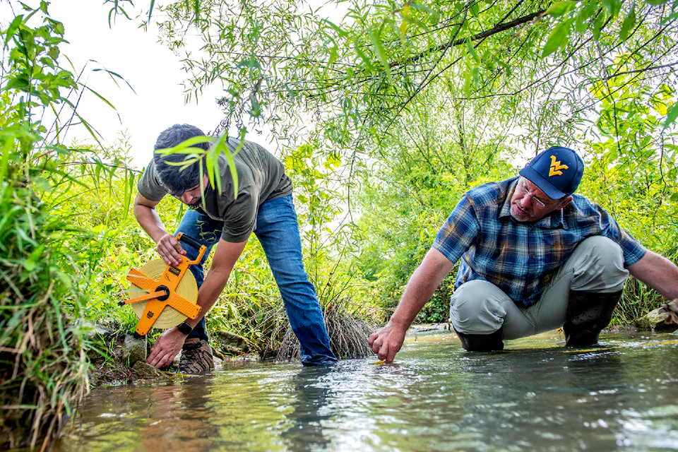 A student and professor working in a local waterway