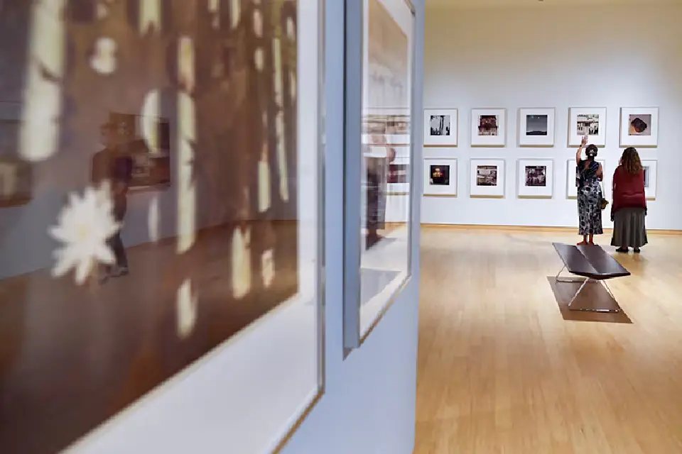Two people view a photography exhibit in a WVU Art Museum gallery.
