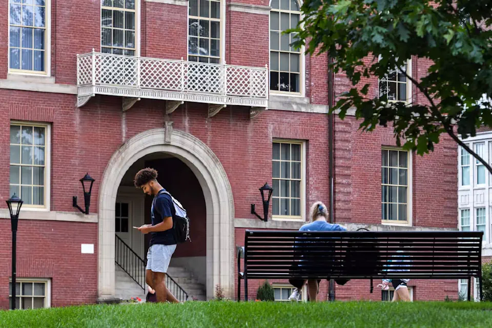 A person looks down at their phone while walking past Chitwood Hall in Woodburn Circle