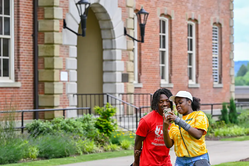 Two prospective students look at their phone while touring Woodburn Circle