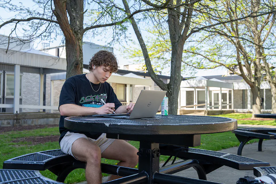 Student studying on their laptop at a picnic table