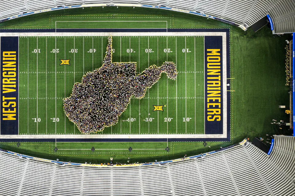 Class of 2029 gathers on the Milan Puskar Stadium field in the shape of the state of West Virginia