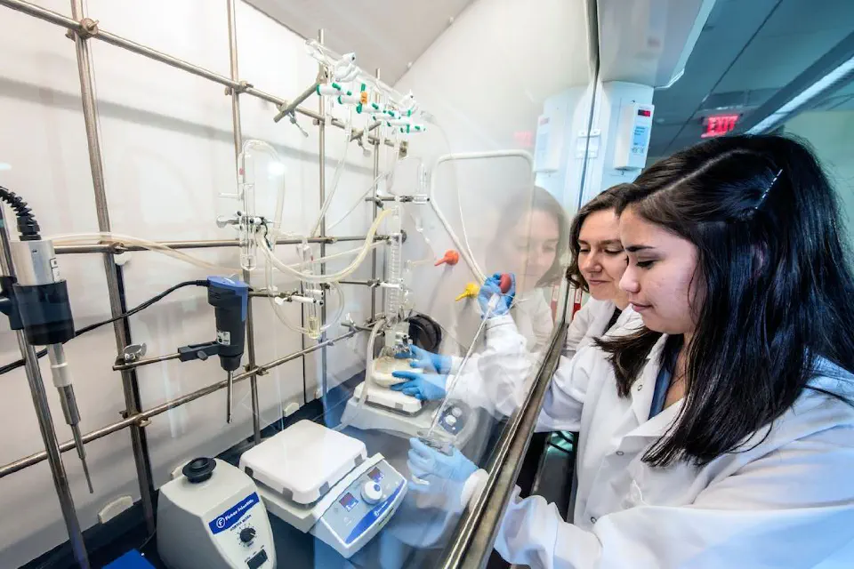 Two people in white lab coats working in a lab