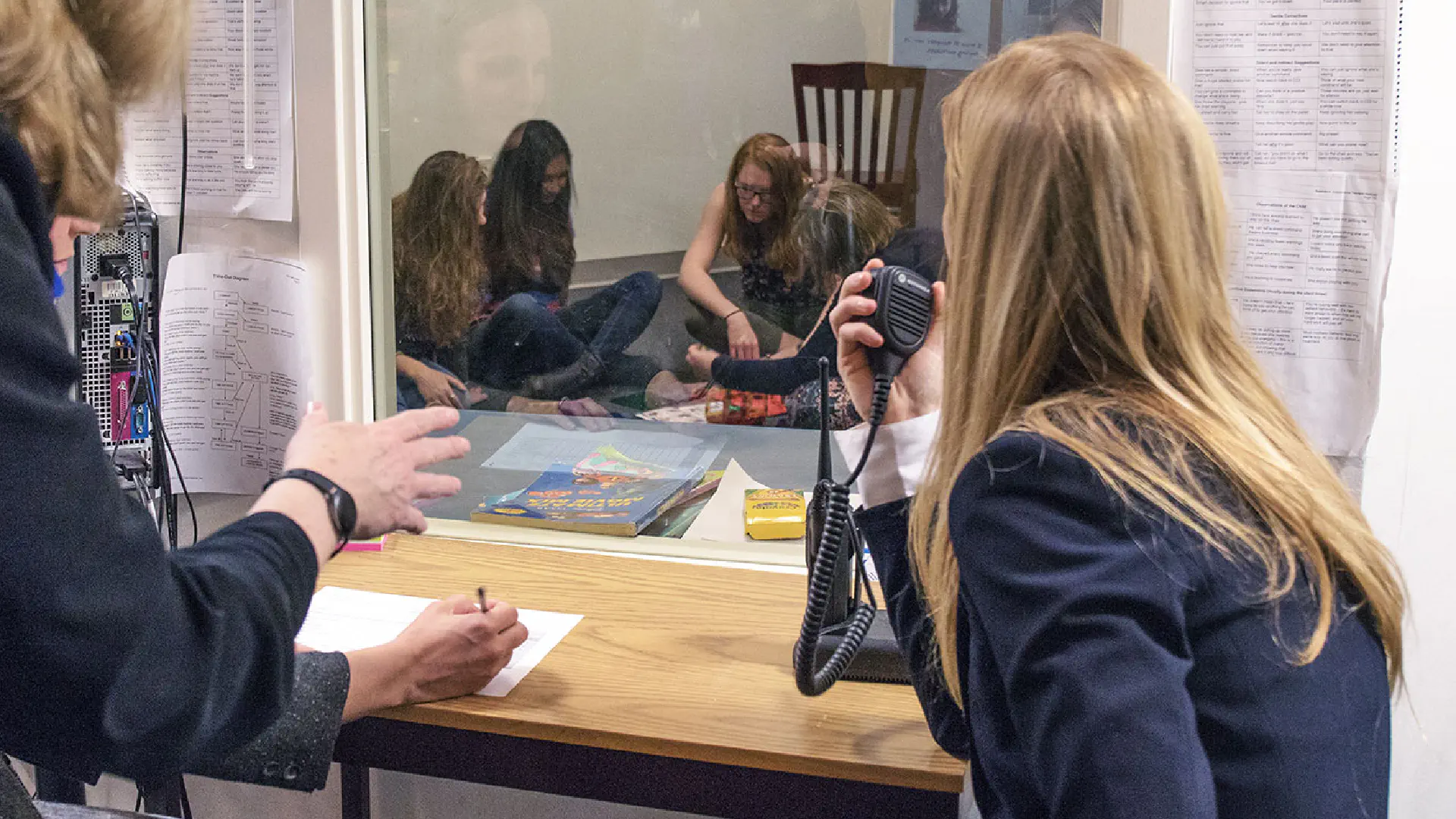 Person in observation room using a device to speak to study participants.