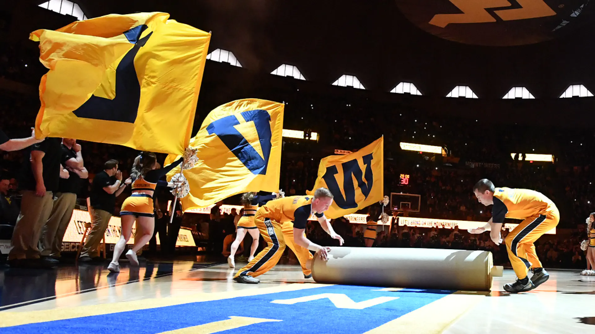 Cheerleaders roll out the gold and blue carpet during pregame in the WVU Coliseum