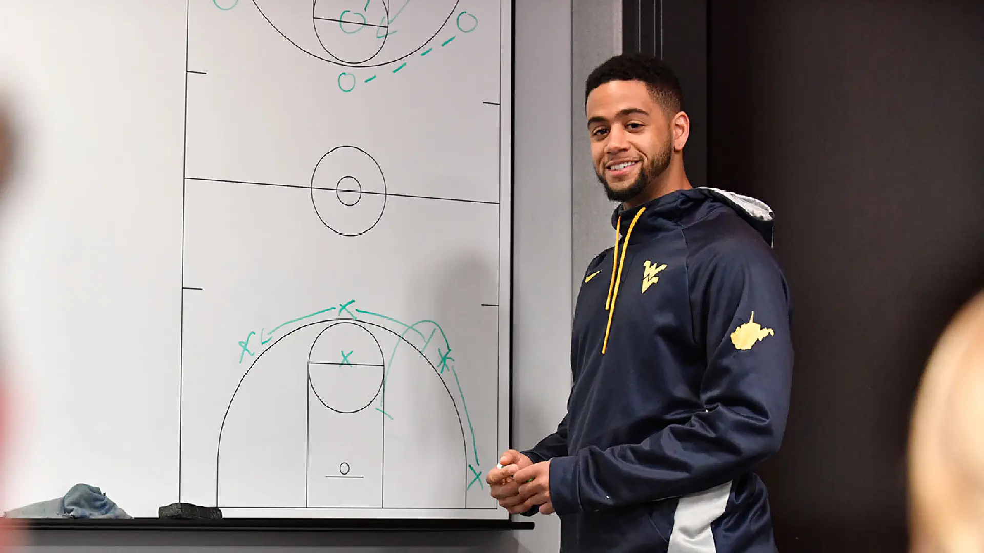 Person standing by whiteboard with outline of basketball court