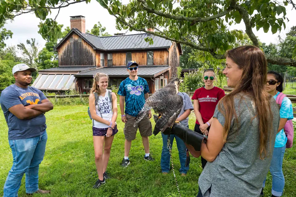 Students interact with a wildlife expert handling a bird of prey