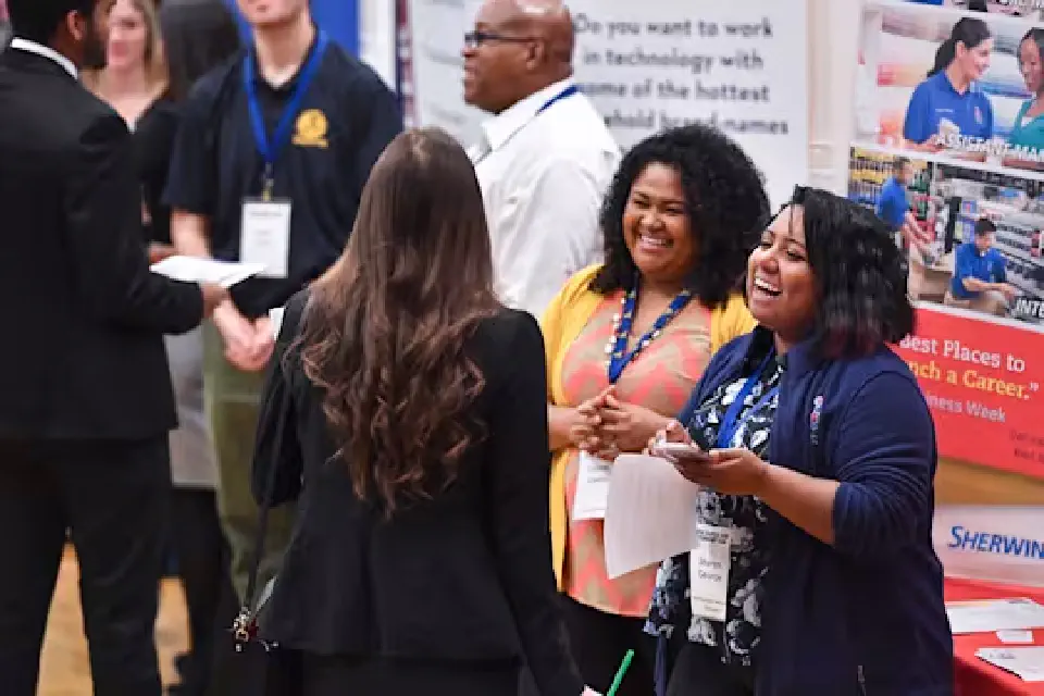 A student talks to Sherwin Williams representatives at a career fair