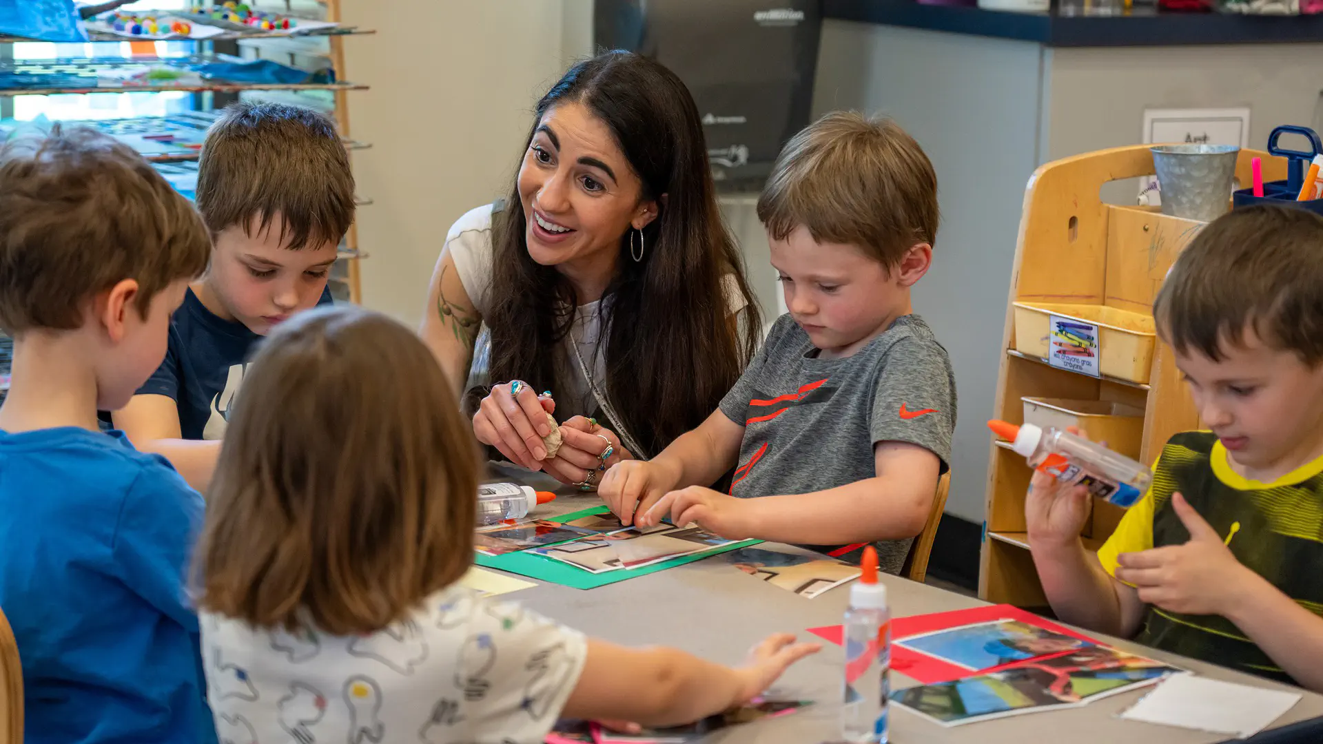 Student helping nursery school students with a craft project