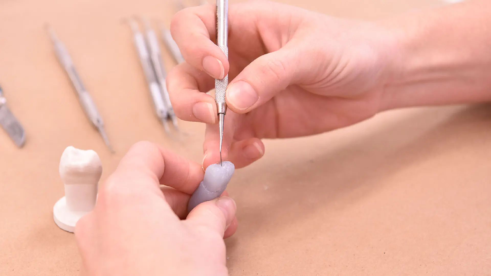 Dental hygiene student uses a tool to scrape a model of a tooth