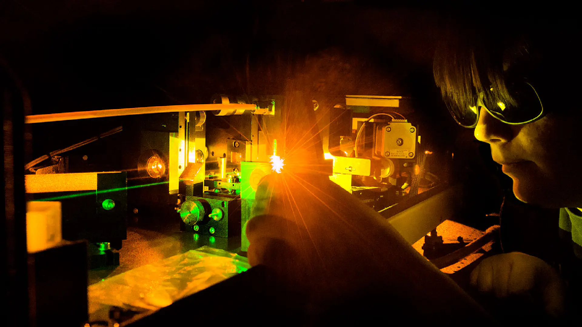 Person using lasers in darkened laboratory.
