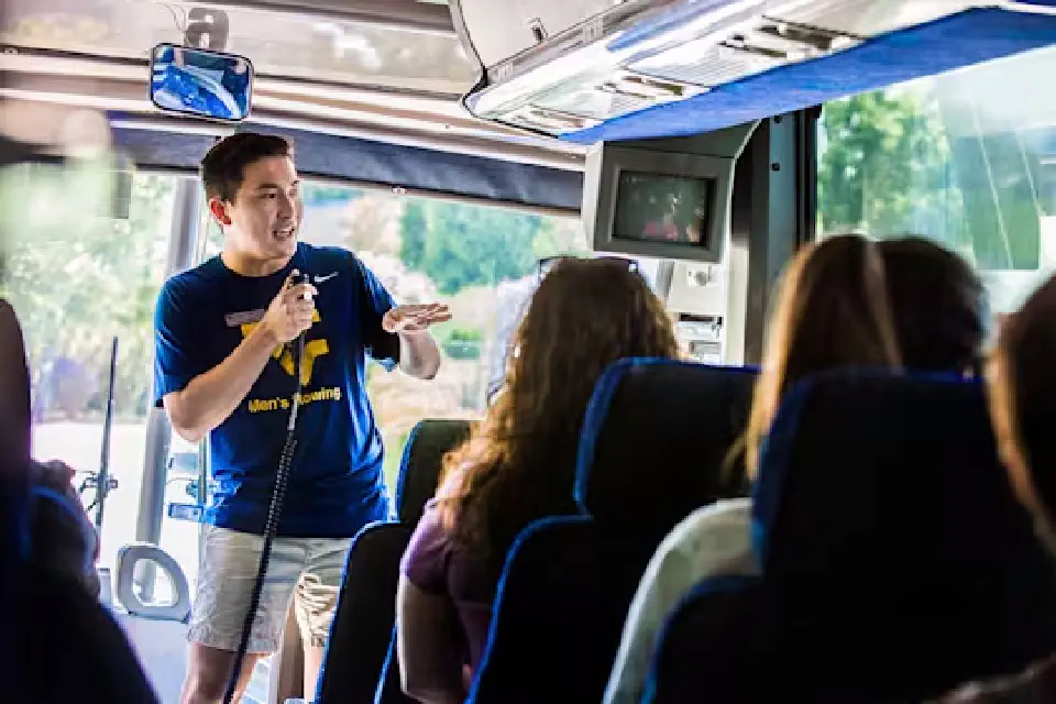 WVU tour guide uses microphone to speak to visitors on tour bus